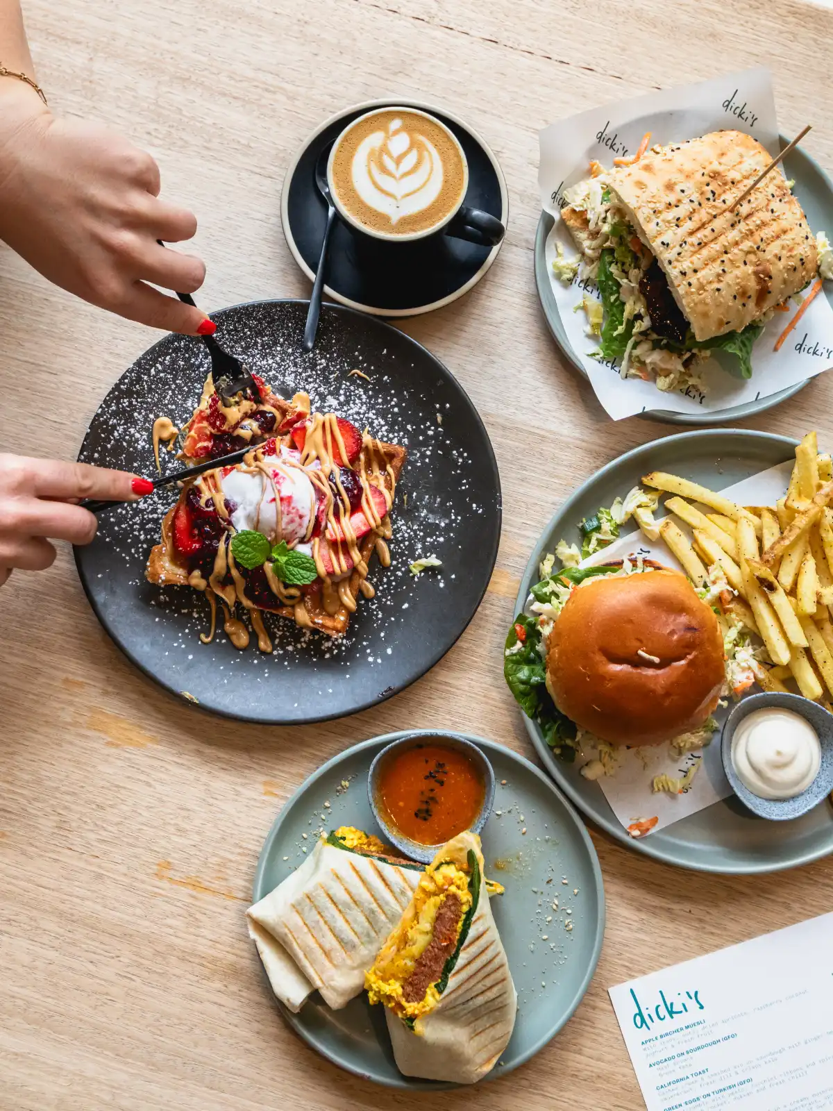 Professional flatlay food photography featuring a spread of vegan burgers, waffles, and coffee for restaurant marketing